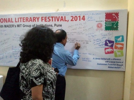 Ramesh Menon signs the authors' board while Manjiri Prabhu looks on.