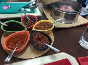 Five types of sauces at Yum Yum Cha, with pink crab dumplings in the background.